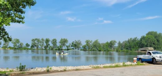 Grand Lake St. Marys being treated with one of the phosphorous binding treatments (Phoslock) in early June 2021. Two researchers stand on a boat spraying the treatment into the water.